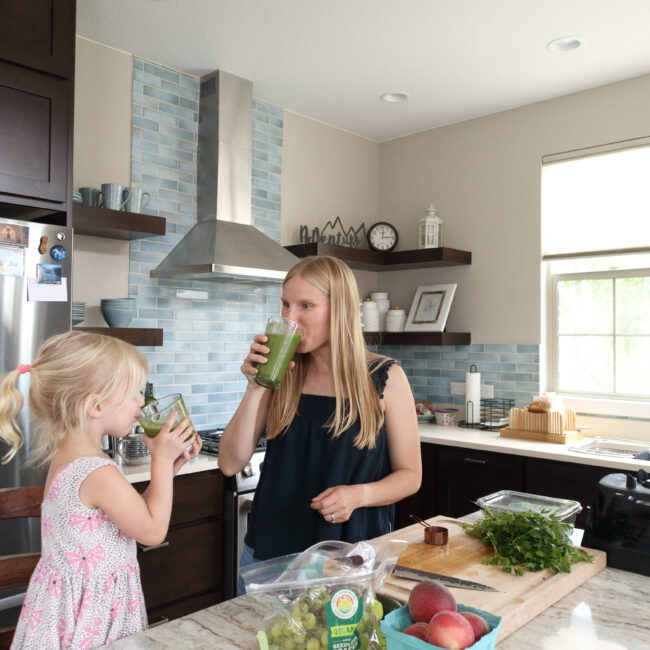 Alison Percowycz, MSN, FNP-C drinking a smoothie in a kitchen with a child