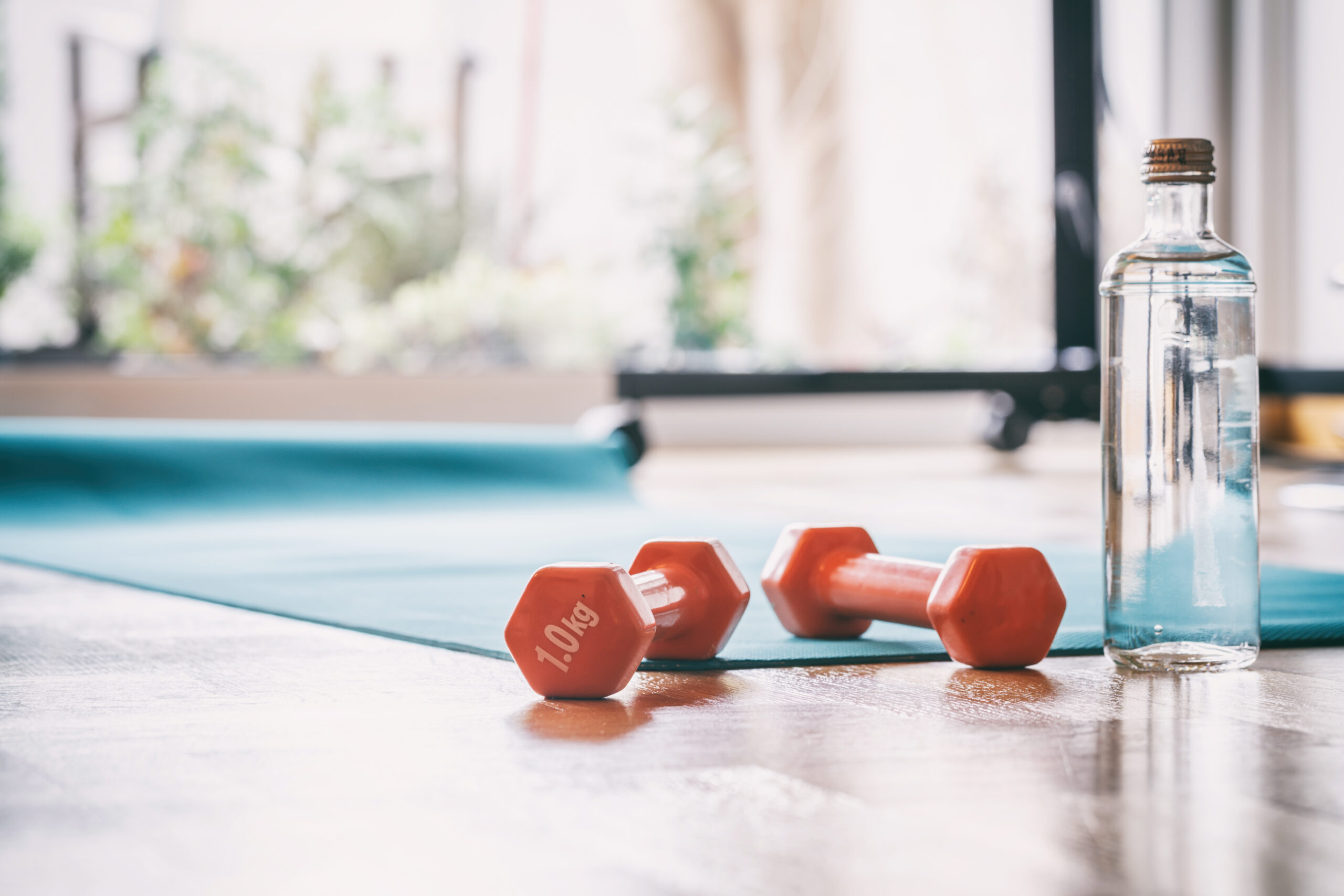 a yoga mat with a pair of weights and a water bottle on a wooden floor