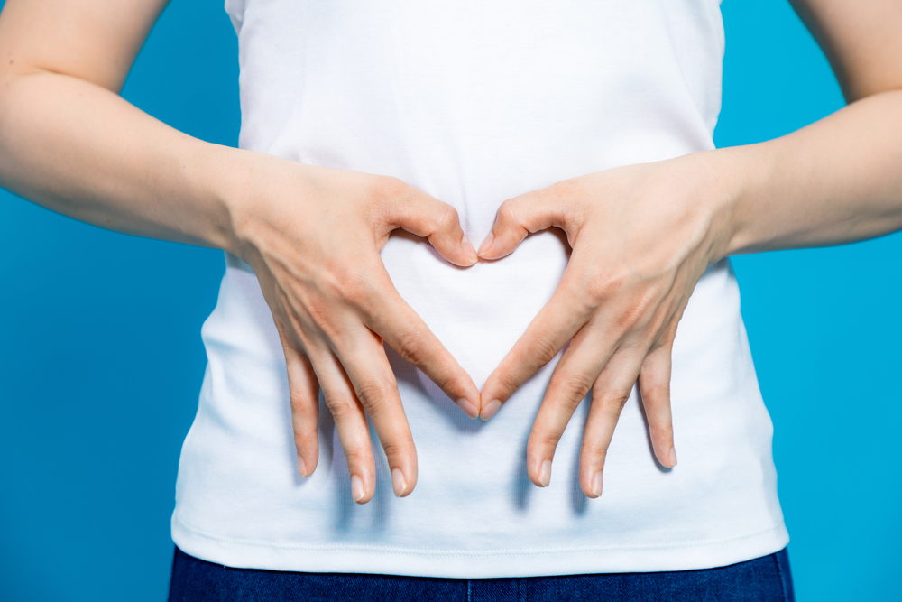closeup of a woman holder her hands in a heart shape over her stomach